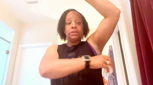 Person wearing a black sleeveless top with a graphic design indoors.