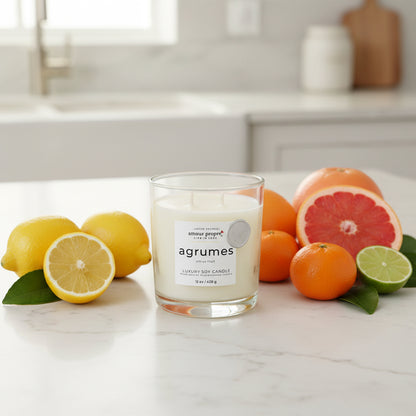 Candle labeled 'agrumes' surrounded by citrus fruits on a kitchen counter.