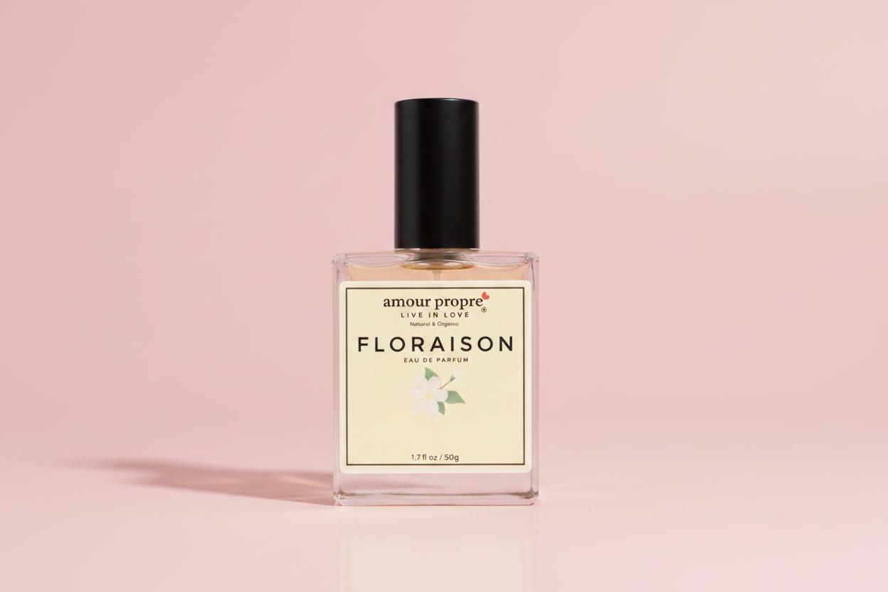 Hand holding a perfume bottle labeled 'Floraison' against a green leafy background