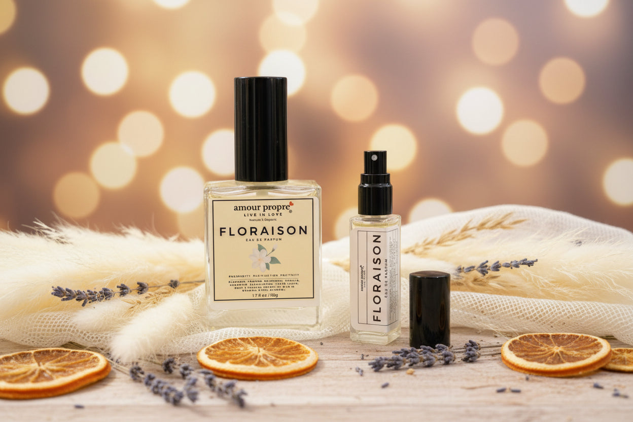 Floraison perfume bottles on a wooden surface with dried oranges and lavender, blurred lights in the background