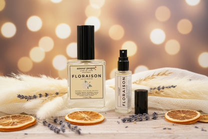 Floraison perfume bottles on a wooden surface with dried oranges and lavender, blurred lights in the background