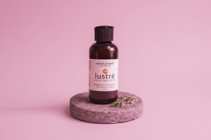 Bottle of 'Lustre' on a stone platform with a pink background